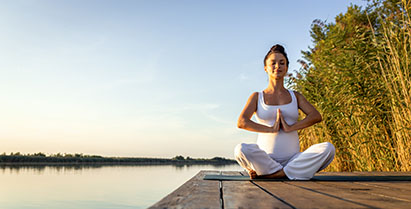 Pregnant woman doing yoga at lake during the day