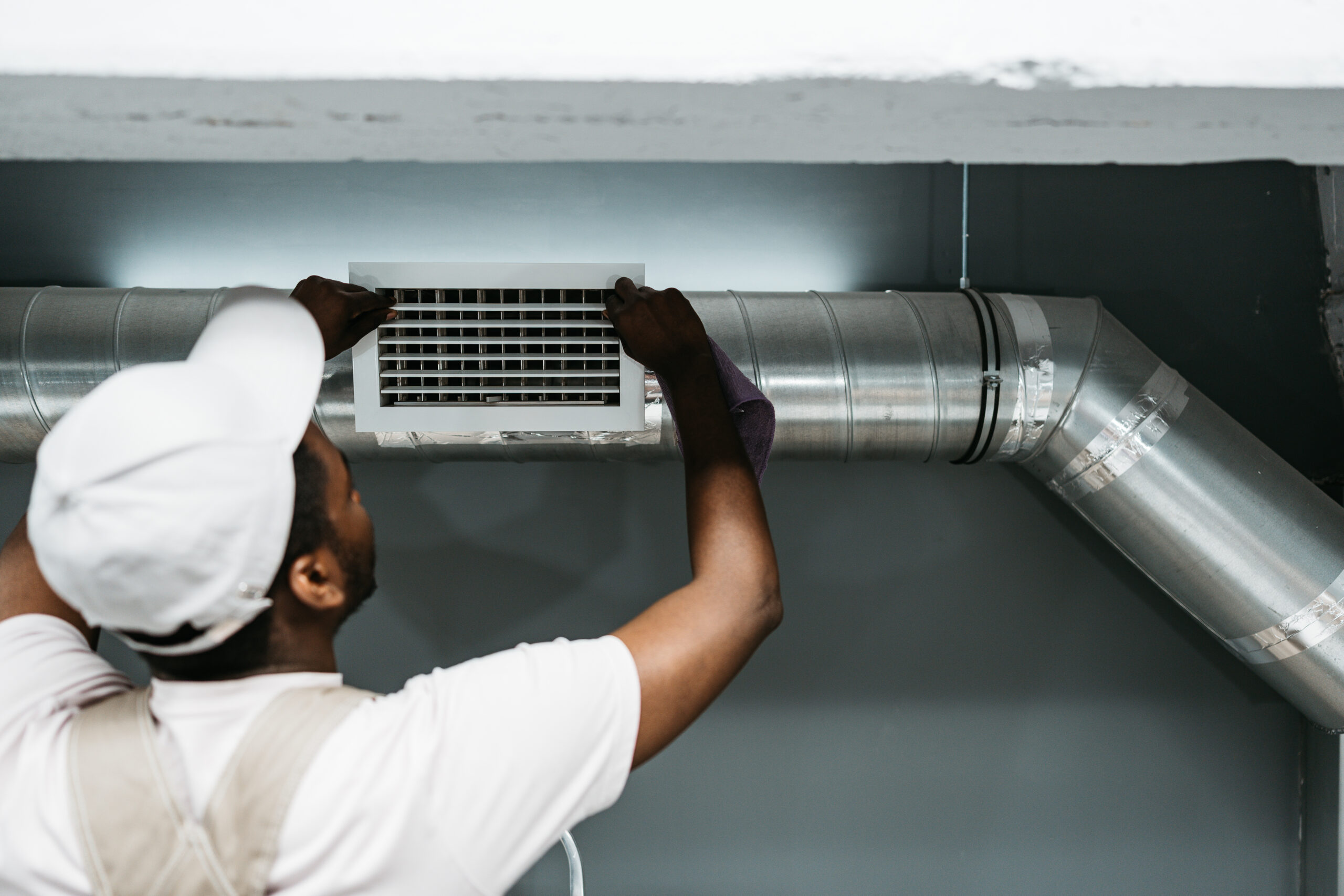 Technician performs air duct installation in a residential building during daylight hours