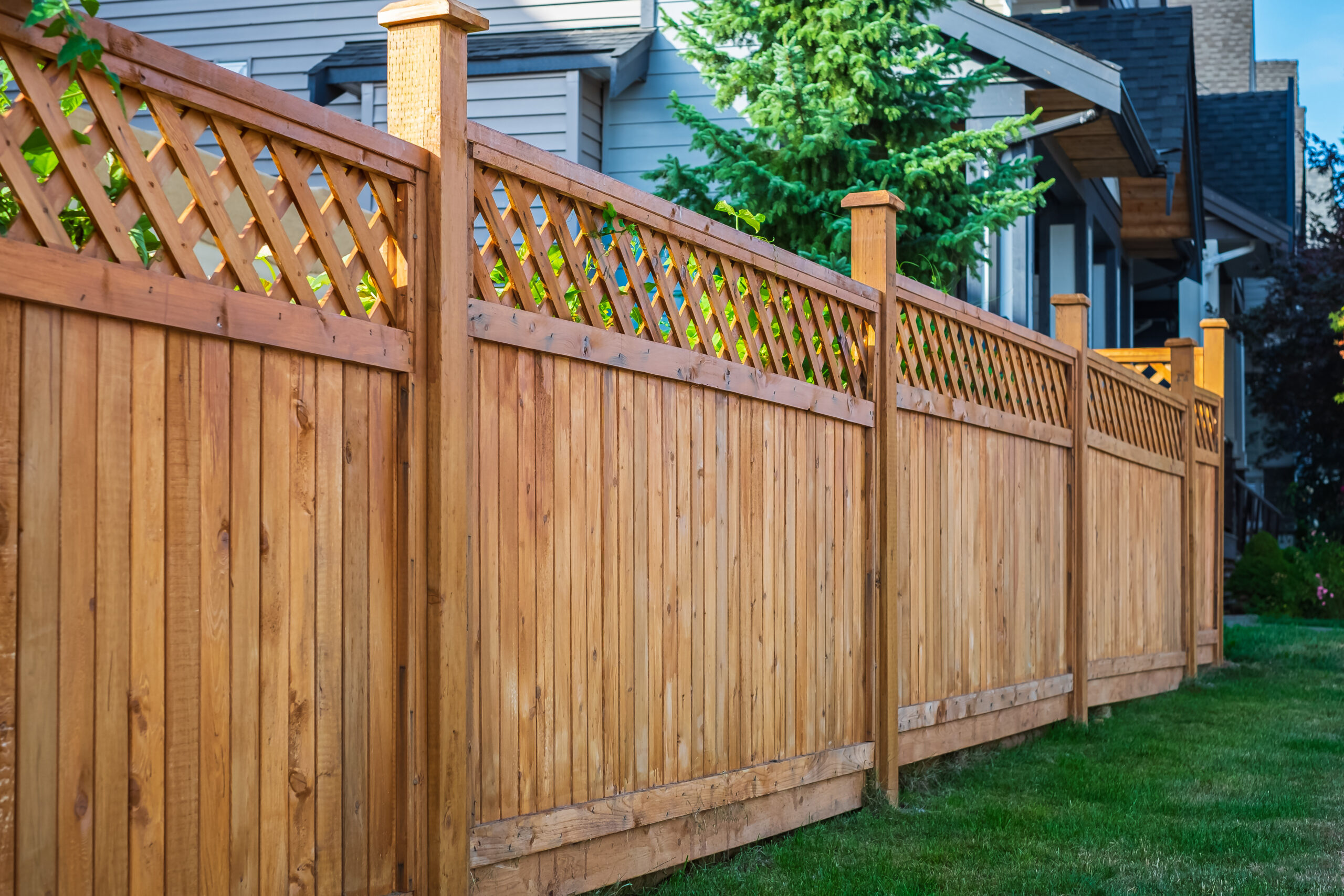 Nice new wooden fence around house. Wooden fence with green lawn
